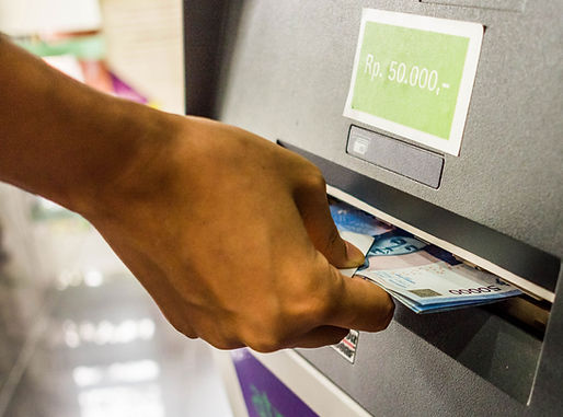 Mão retirando dinheiro de um caixa eletrônico, simbolizando o serviço de remessas internacionais para saque no exterior