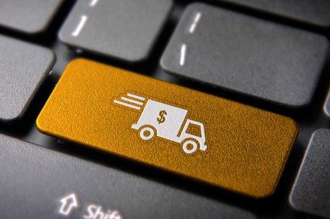 Tecla dourada de um teclado com o símbolo de um caminhão de delivery de dinheiro, representando a opção de receber moedas estrangeiras em casa